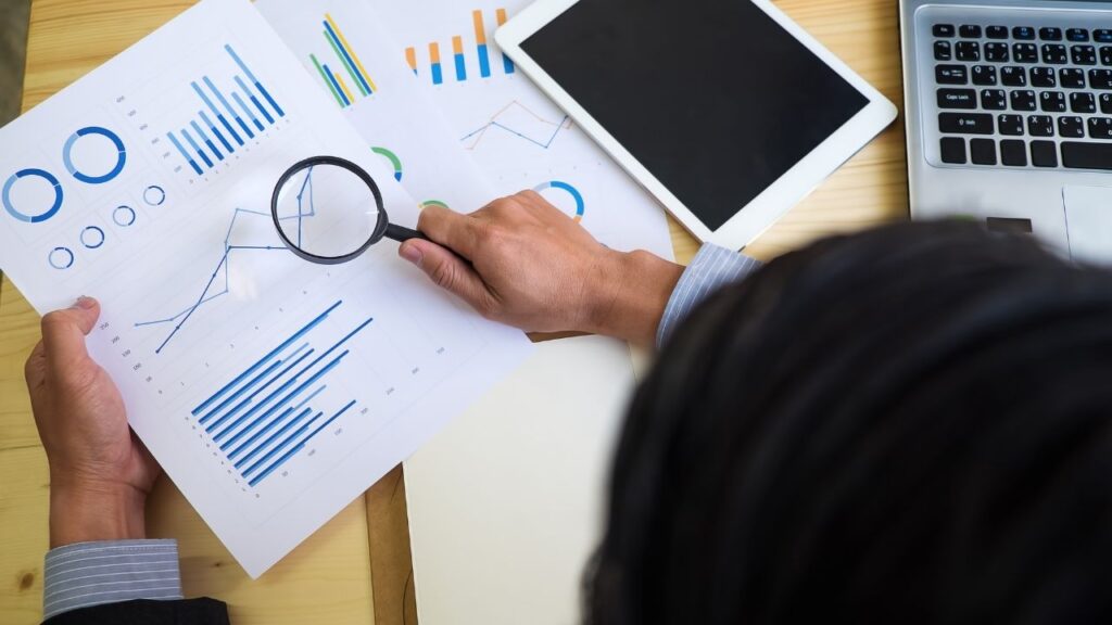 birds eye view of person holding a magnifying glass over a piece of paper with affordability graphs on it