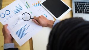 birds eye view of person holding a magnifying glass over a piece of paper with affordability graphs on it