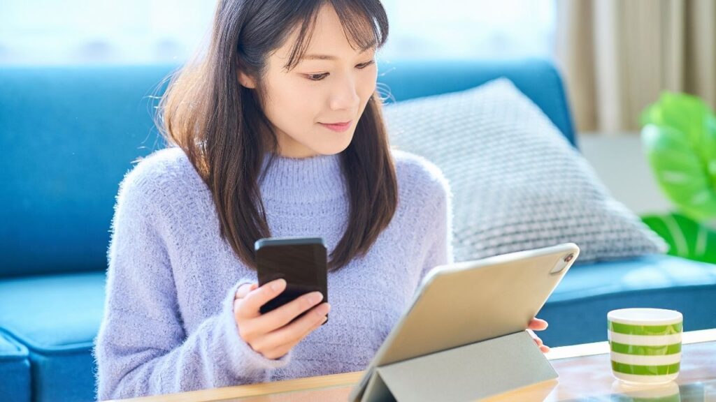woman holding phone and looking at tablet