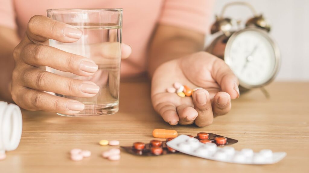 person holding glass of water and medication
